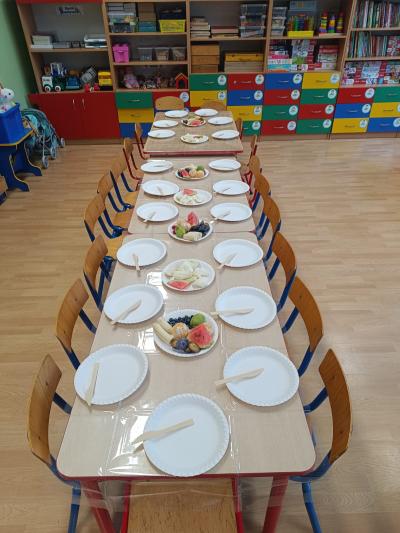 Stoły z pustymi talerzami i owocami.