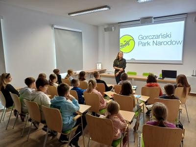 Uczniowie siedzą w sali Gorczańskiego Parku Narodowego.