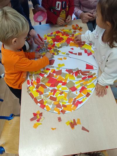 Dzieci wyklejają dynię małymi kawałeczkami bibiły.