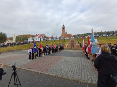 Poczty sztandarowe stoją przed pamiątkową tablicą, upamiętniającą tych, którzy walczyli w obronie Ojczyzny.