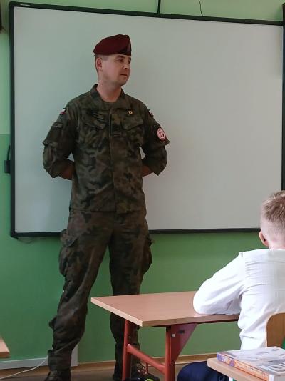 Żołnierz stoi przed tablicą w klasie.