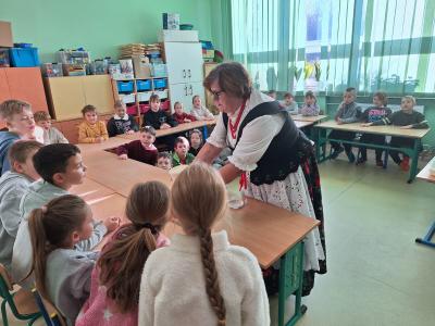 Pani z Koła Gospodyń Wiejskich pokazuje dzieciom zrobione masło.