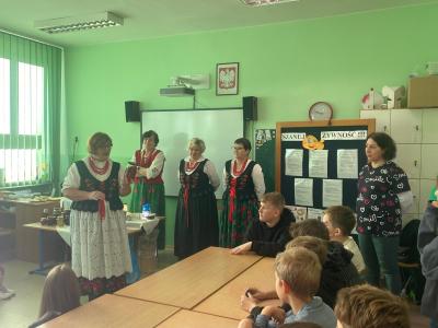 Pani z Koła Gospodyń Wiejskich opowiada o przetworach i pokazuje kompot w słoiku.