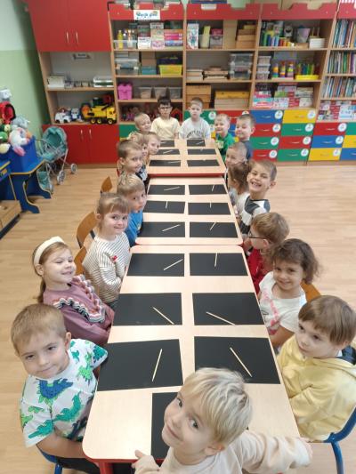 Dzieci siedzą przy stolikach. Na stolikach leżą wydrapywanki.