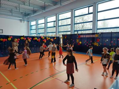 Uczniowie tańczą razem z wyświetlanymi na ekranie instruktorami tańca.