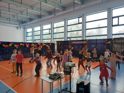 Uczniowie tańczą razem z wyświetlanymi na ekranie instruktorami tańca.