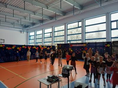 Uczniowie tańczą razem z wyświetlanymi na ekranie instruktorami tańca.