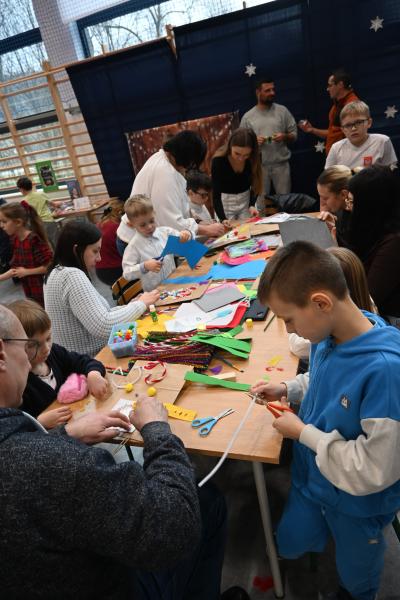 Rodzice wraz z dziećmi ozdabiają papierowe torebki.