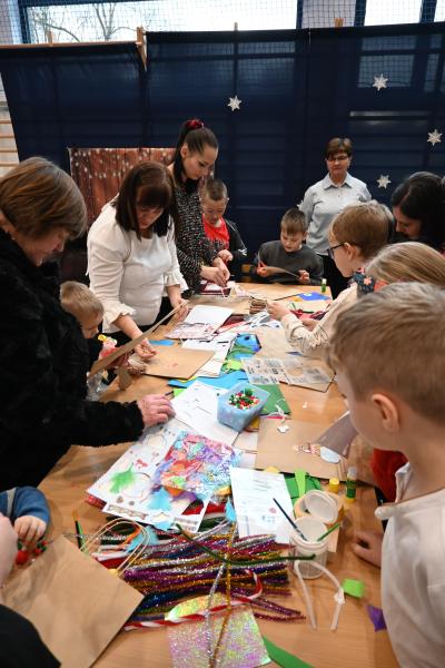 Rodzice wraz z dziećmi ozdabiają papierowe torebki.