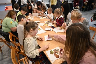 Rodzice wraz z dziećmi ozdabiają pierniczki.