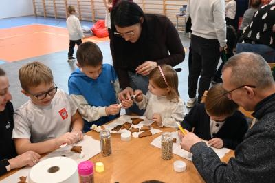Rodzice wraz z dziećmi ozdabiają pierniczki.