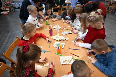 Rodzice wraz z dziećmi kolorują drewniane ozdoby.