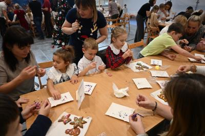 Rodzice wraz z dziećmi ozdabiają pierniczki.