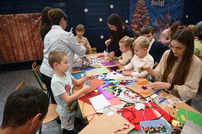 Rodzice wraz z dziećmi ozdabiają papierowe torebki.