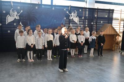 Uczniowie stoją na scenie i recytują swoje role.