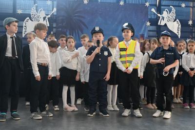 Uczniowie stoją na scenie i recytują swoje role. Trzech uczniów przebranych jest za policjantów.