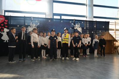 Uczniowie stoją na scenie i recytują swoje role. Trzech uczniów przebranych jest za policjantów.