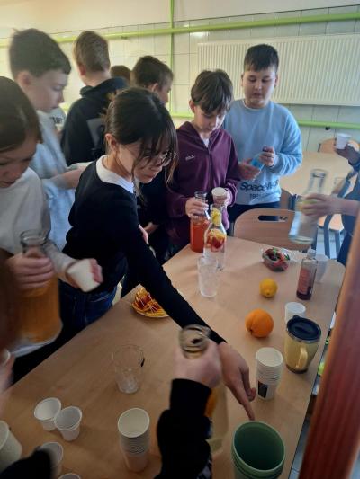 Uczniowie piją wodę z dodatkami.