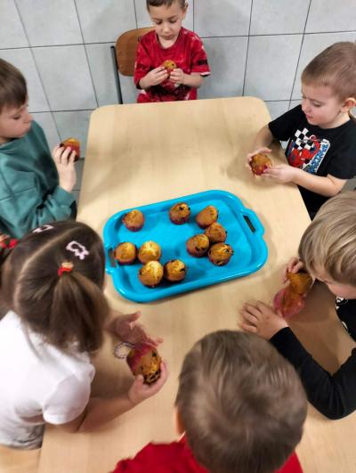 Dzieci jedzą upieczone muffinki.