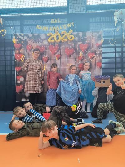 Uczniowie pozują do zdjęcia na tle walentynkowym- w serduszka.