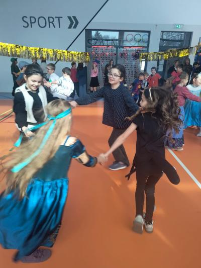 Uczniowie tańczą na sali gimnastycznej.