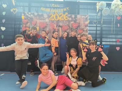 Uczniowie pozują do zdjęcia na tle walentynkowym- w serduszka.