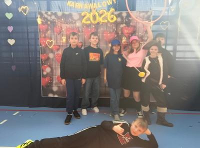 Uczniowie pozują do zdjęcia na tle walentynkowym- w serduszka.