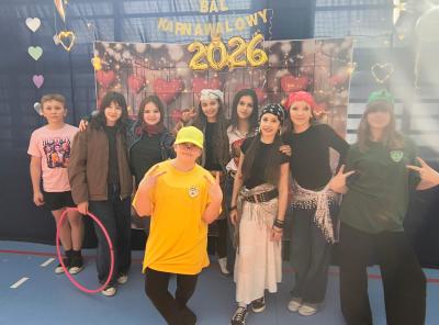 Uczniowie pozują do zdjęcia na tle walentynkowym- w serduszka.