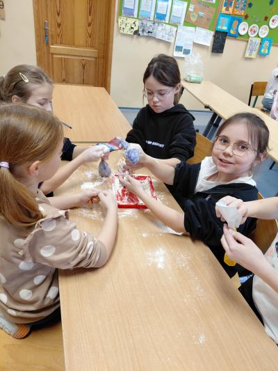 Uczniowie robią gniotki z balonów i mąki.