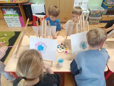 Dzieci malują farbami na płótnie, na sztalugach.