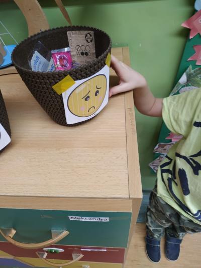 Dziecko wkłada opakowanie po przekąsce do smutnego koszyka.