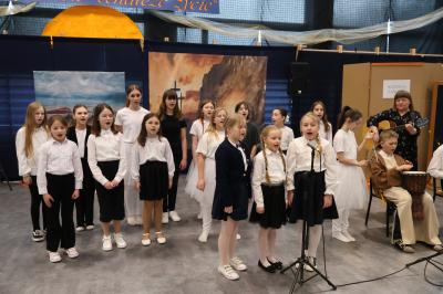 Uczniowie stoją w grupie i śpiewają pieśń.