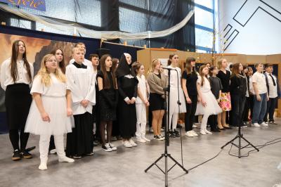 Uczniowie stoją w grupie i śpiewają pieśń.