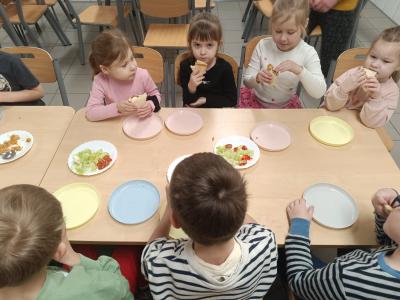 Dzieci jedzą tortille z warzywami i kurczakiem.