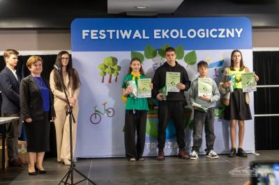 Jury i uczniowie z dyplomami stoją na scenie.