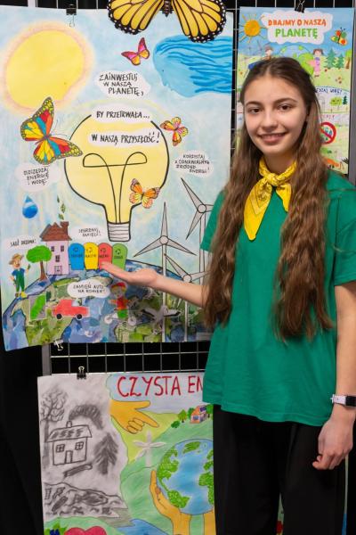 Uczennica wskazuje swój plakat w galerii prac.