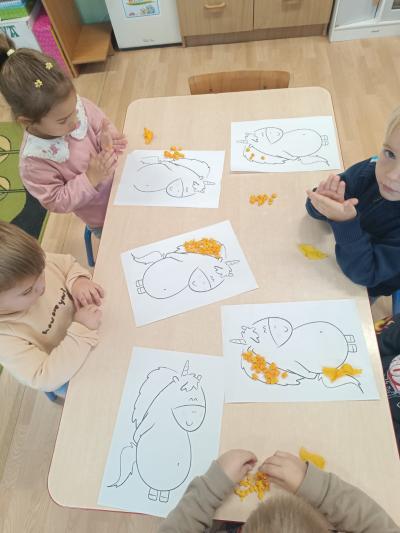 Dzieci wyklejają grzywę Gucia żółtymi kulkami z bibuły.