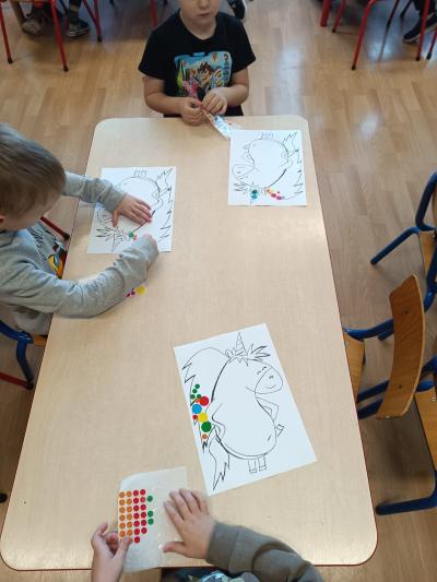 Dzieci wyklejają grzywę Gucia kolorowymi kropeczkami.