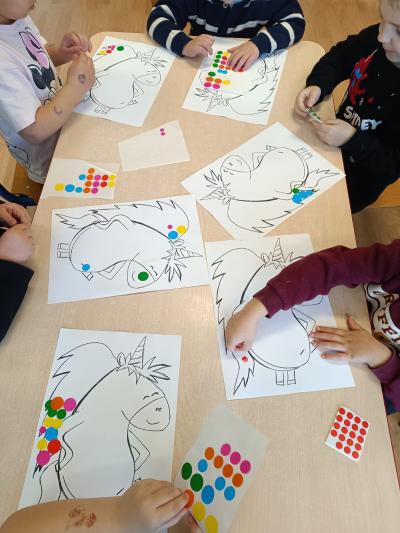 Dzieci wyklejają grzywę Gucia kolorowymi kropeczkami.