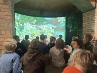 Przedszkolaki oglądają film o pszczołach, ich roli w przyrodzie oraz pracy pszczelarza.