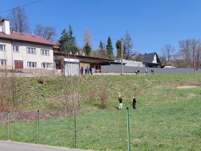 Uczniowie sprzątają teren wzdłuż drogi głównej.