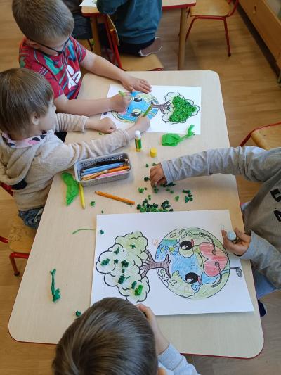 Dzieci wykonują pracę plastyczną przy stoliku.