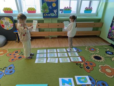 Dzieci poruszają się ścieżką edukacyjną na dywanie.