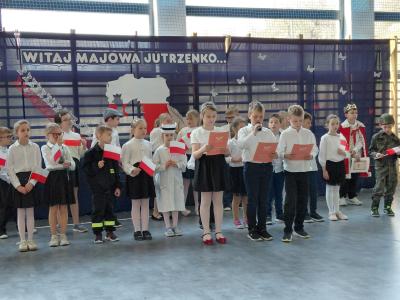 Uczniowie stoją na scenie i przybliżają historię świąt majowych.