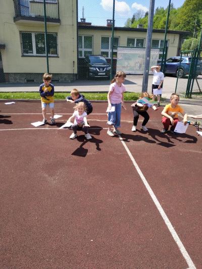 Uczniowie wykonują ćwiczenia na boisku sportowym.