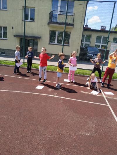 Uczniowie wykonują ćwiczenia na boisku sportowym.
