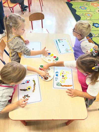 Dzieci wykonują pracę plastyczną - malują palcami na kartce.