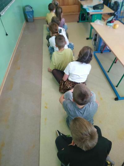 Dzieci siedzą na podłodze jeden za drugim.